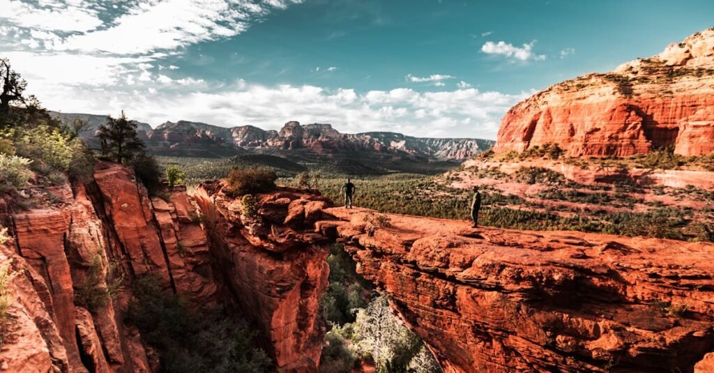 Explorers hiking on Sedona's stunning red rock formations under a vibrant sky.