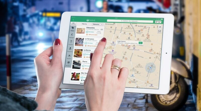 Hands using a digital map on a tablet in an urban setting at night, illustrating navigation and technology.