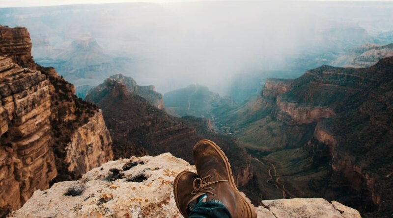 Brown boots on a rocky perch overlooking the vast Grand Canyon landscape.