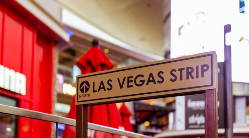 Iconic Las Vegas Strip sign with vibrant city life background.
